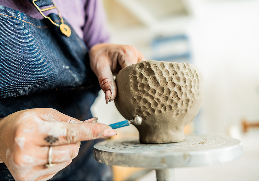 Person shaping a ceramic bowl.