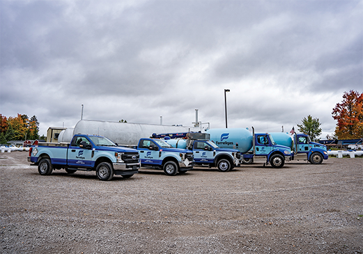A fleet of Ferrellgas delivery trucks parked outside of a propane storage facility.