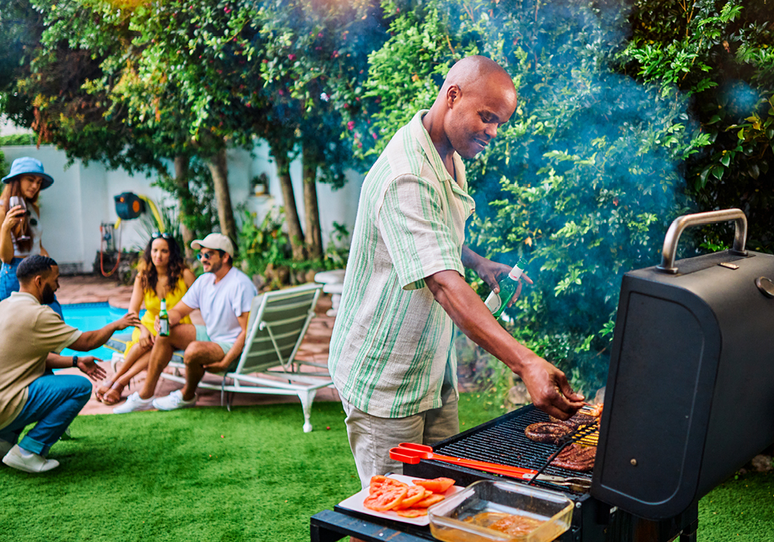 A man is cooking food on a propane-powered grill.