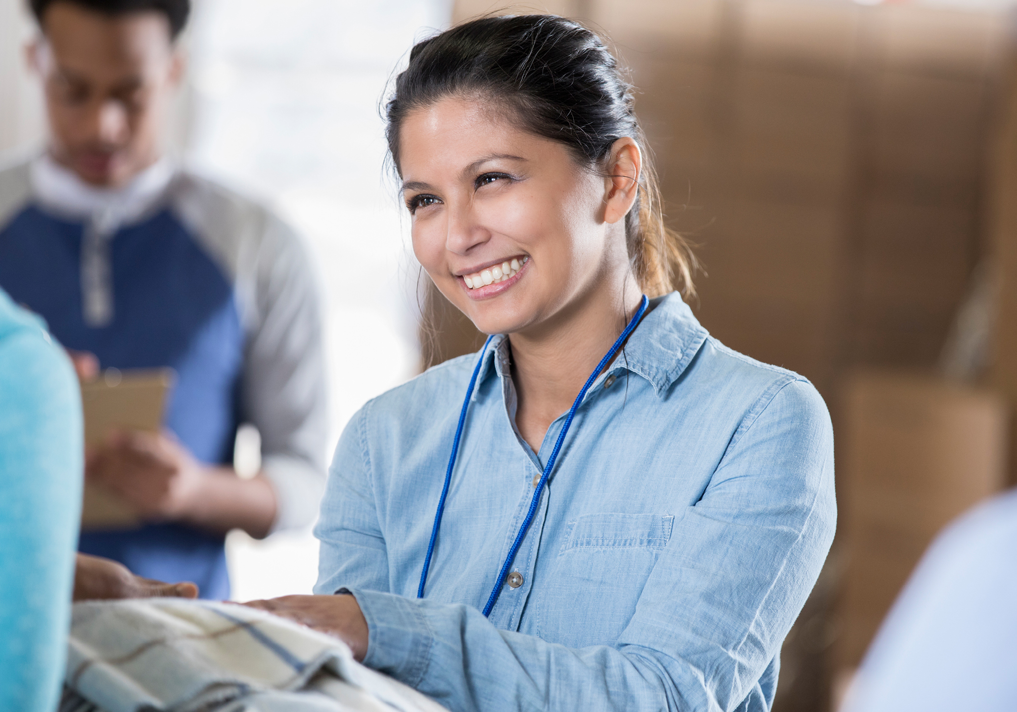Women picking up a blanket and smiling.
