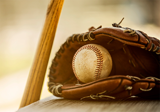 Close-up of baseball, glove, and bat on a table.